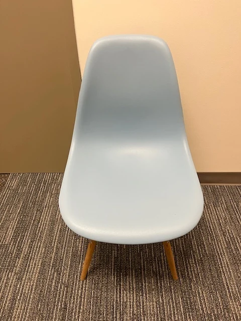 Pale-blue Eames chair standing on a dark carpet sample
