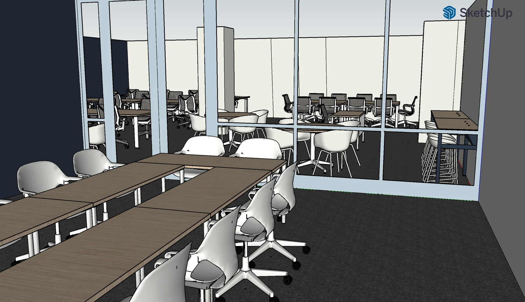 A view from the learning lab across project tables through the glass toward lower round-table seating.