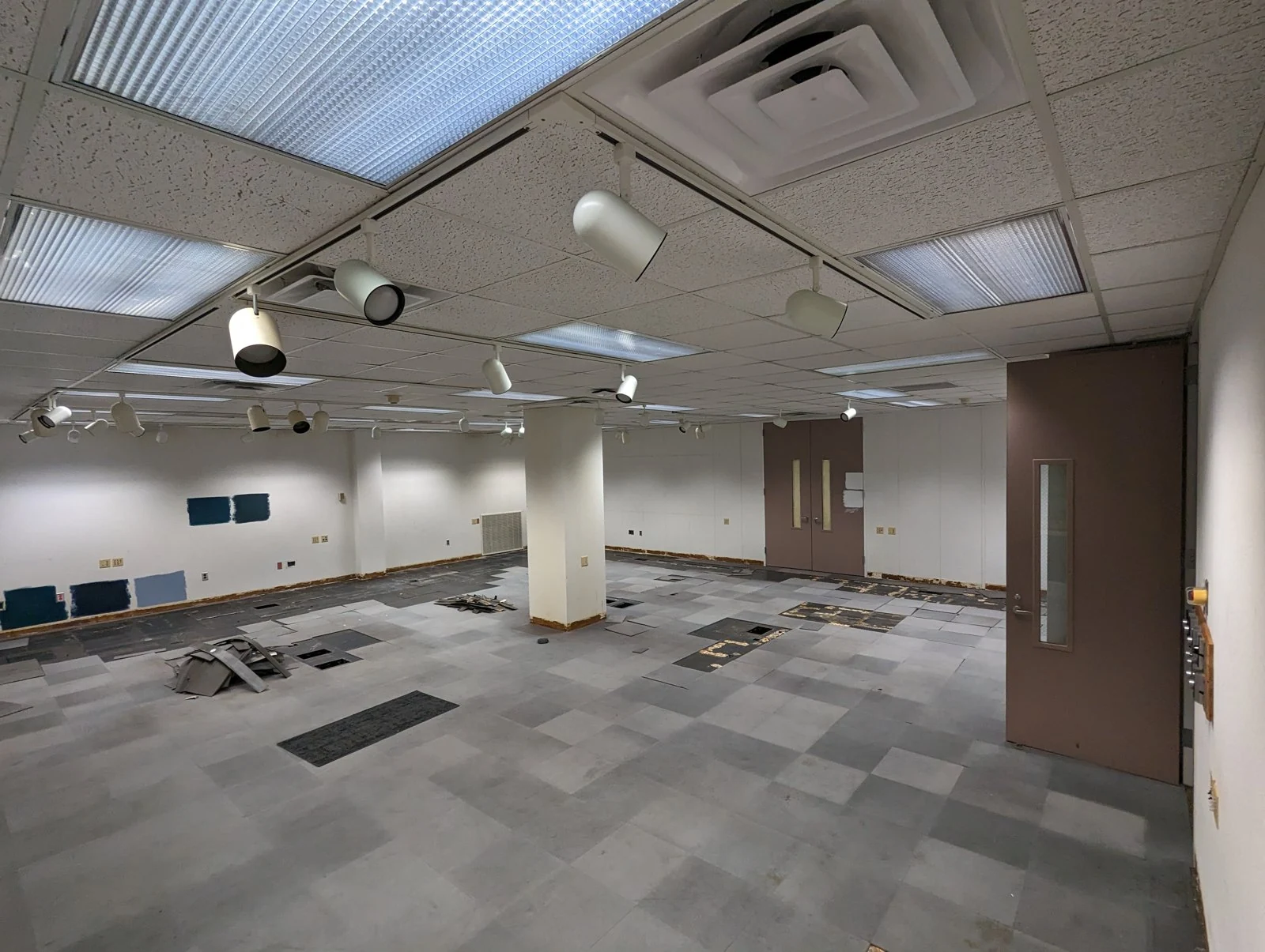 An emptied lab with exposed floor sections and finish samples on the walls