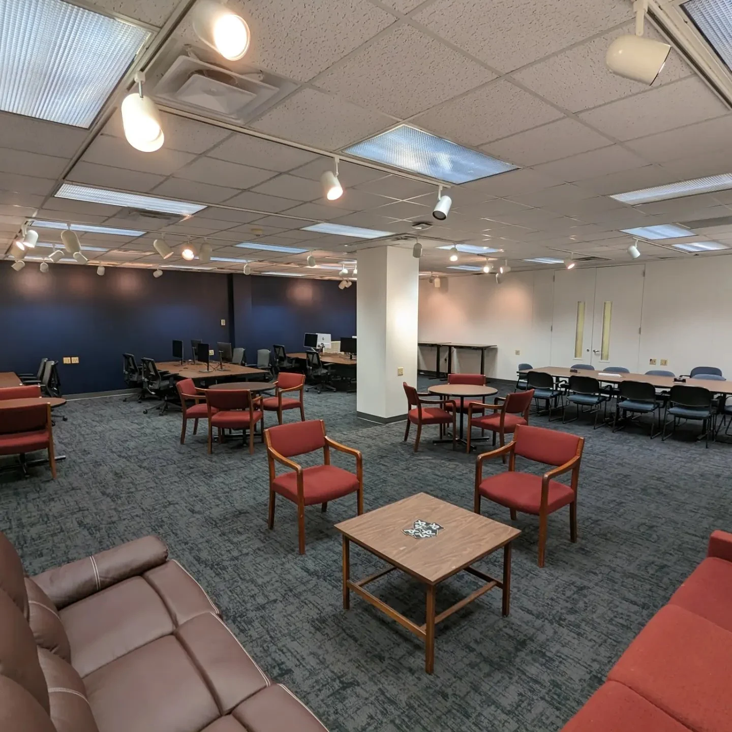 The furnished interim lab with a navy wall, reused red chairs, sofas and perimeter workstations