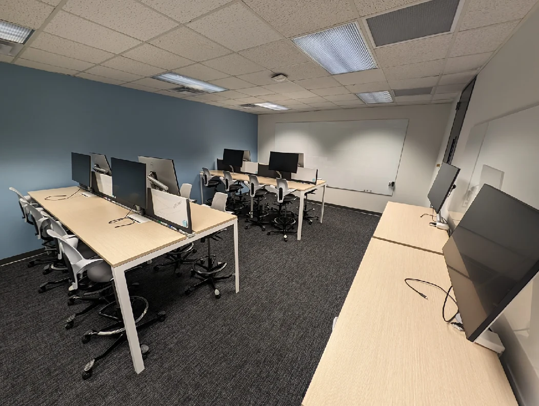 Sitterson 136 after renovation, with monitor-equipped benches, rolling chairs and blue accent walls.