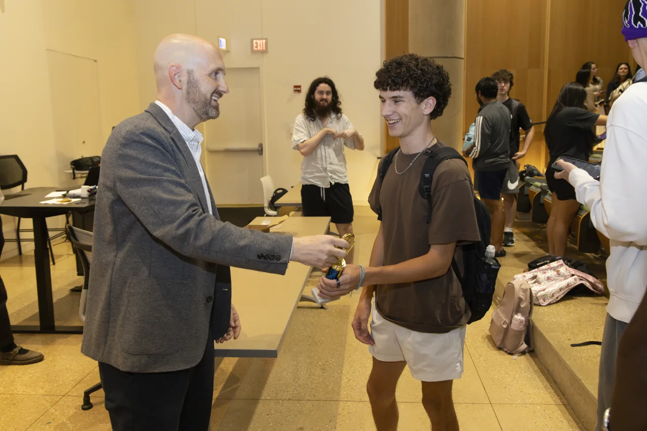 A trophy presentation and handshake at the front of the room